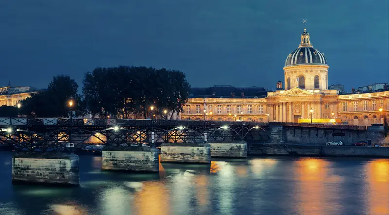 The domed Institut de France and Pont des Arts lit at blue hour over the Seine