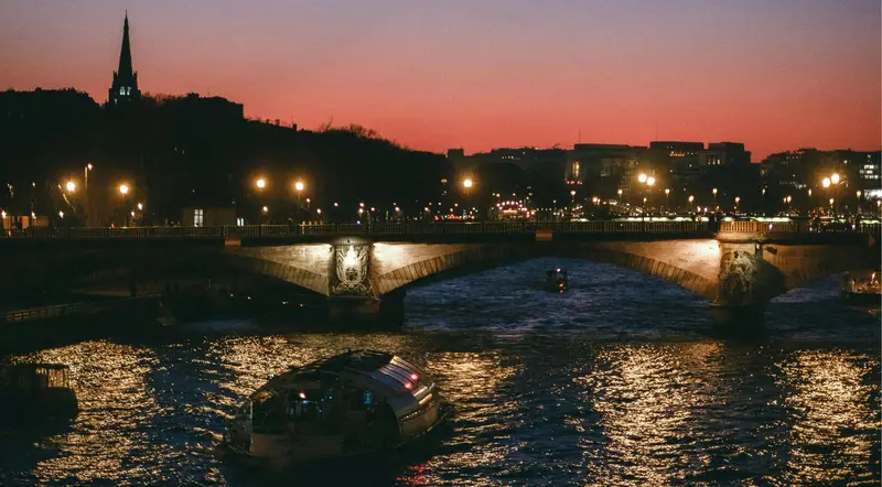 A pink dusk sky over the Seine with small cruise boats in Paris