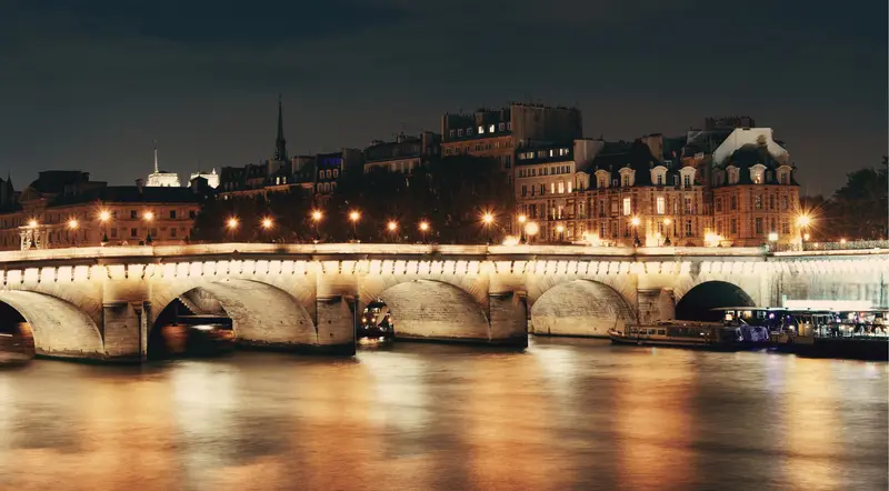 Pont Neuf lit at night with the Eiffel Tower in the distance over the Seine